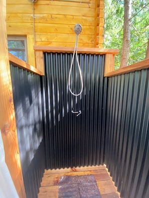 A wooden cabin with a metal door and a metal handle.