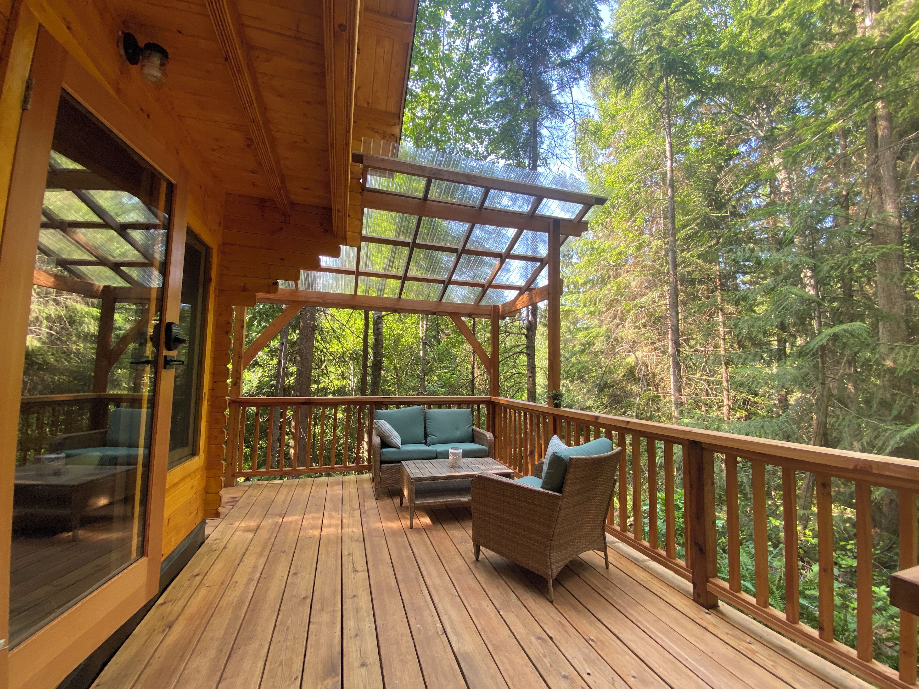 A wooden deck with a glass enclosure, a sofa, and a table.