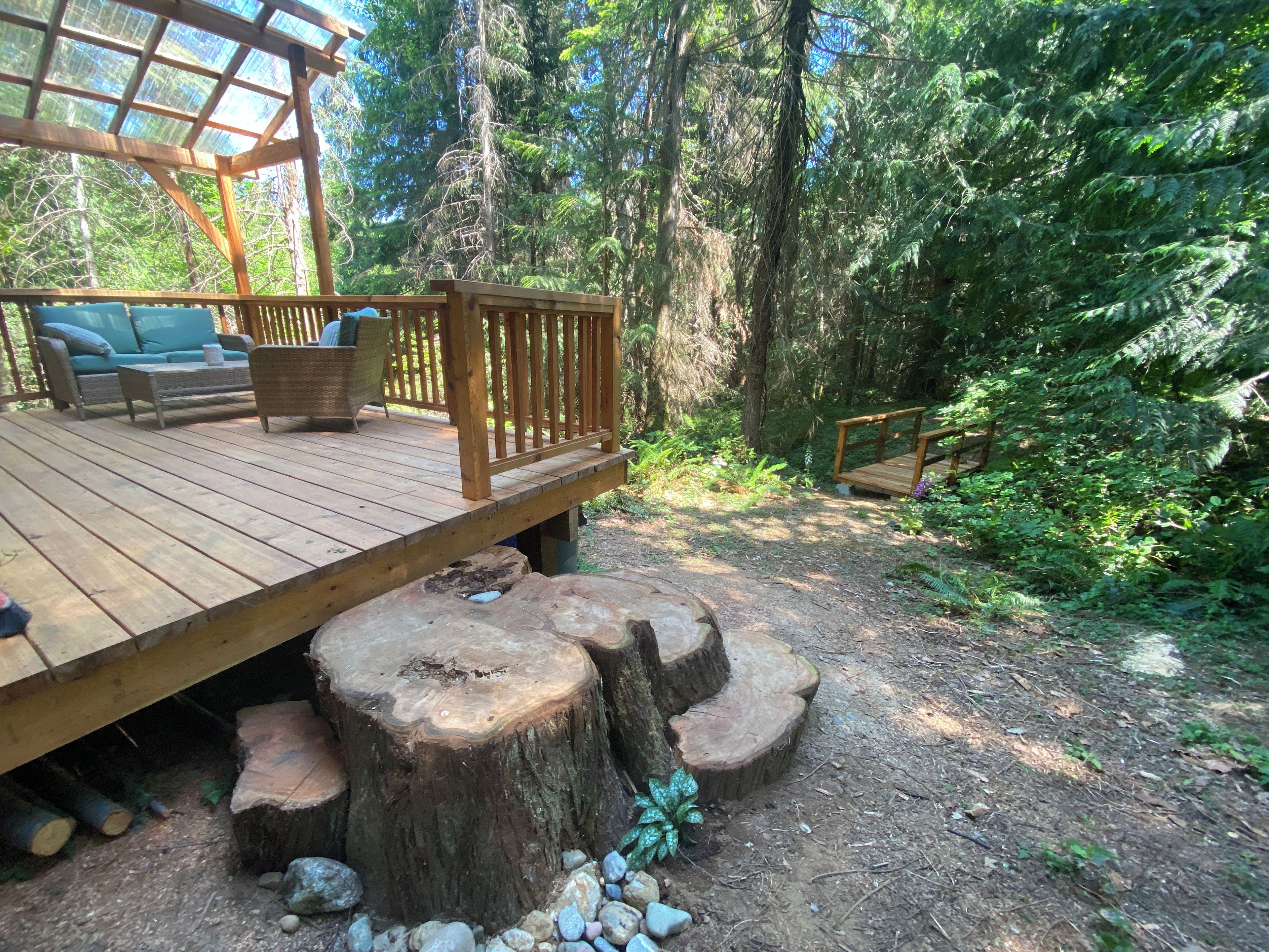 A wooden deck with outdoor furniture, surrounded by a forest.