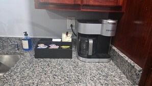 A kitchen with a coffee maker, a soap dispenser, and a box of tea bags.
