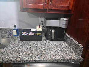 A kitchen with a coffee maker, a soap dispenser, and a box of tea bags.
