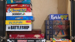 A collection of board games stacked in a cabinet.