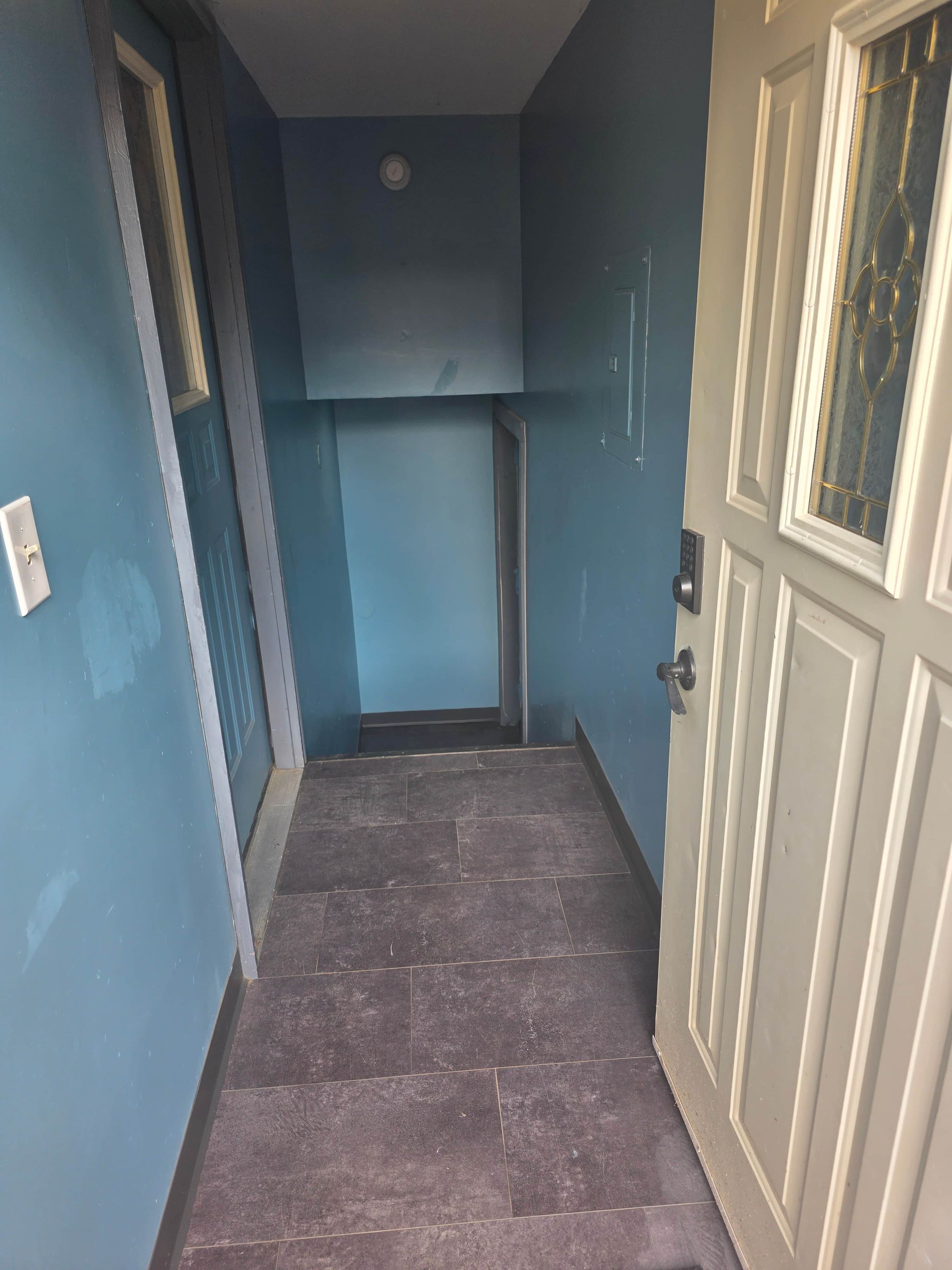 A hallway with a door on the right and a window on the left.