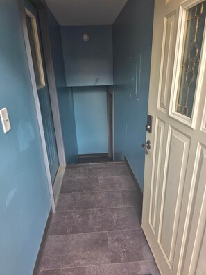 A hallway with a door on the right and a window on the left.