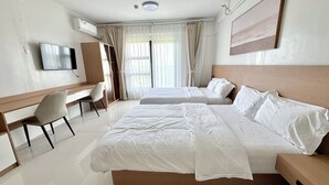 A hotel room with two beds, a desk, a chair, a TV, and a painting on the wall. - Royal Oceancrest Panglao 1 (Dauis)