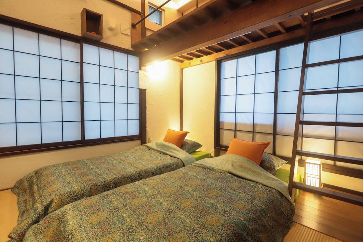 Una habitación con dos camas, una ventana con vistas y techo de madera.