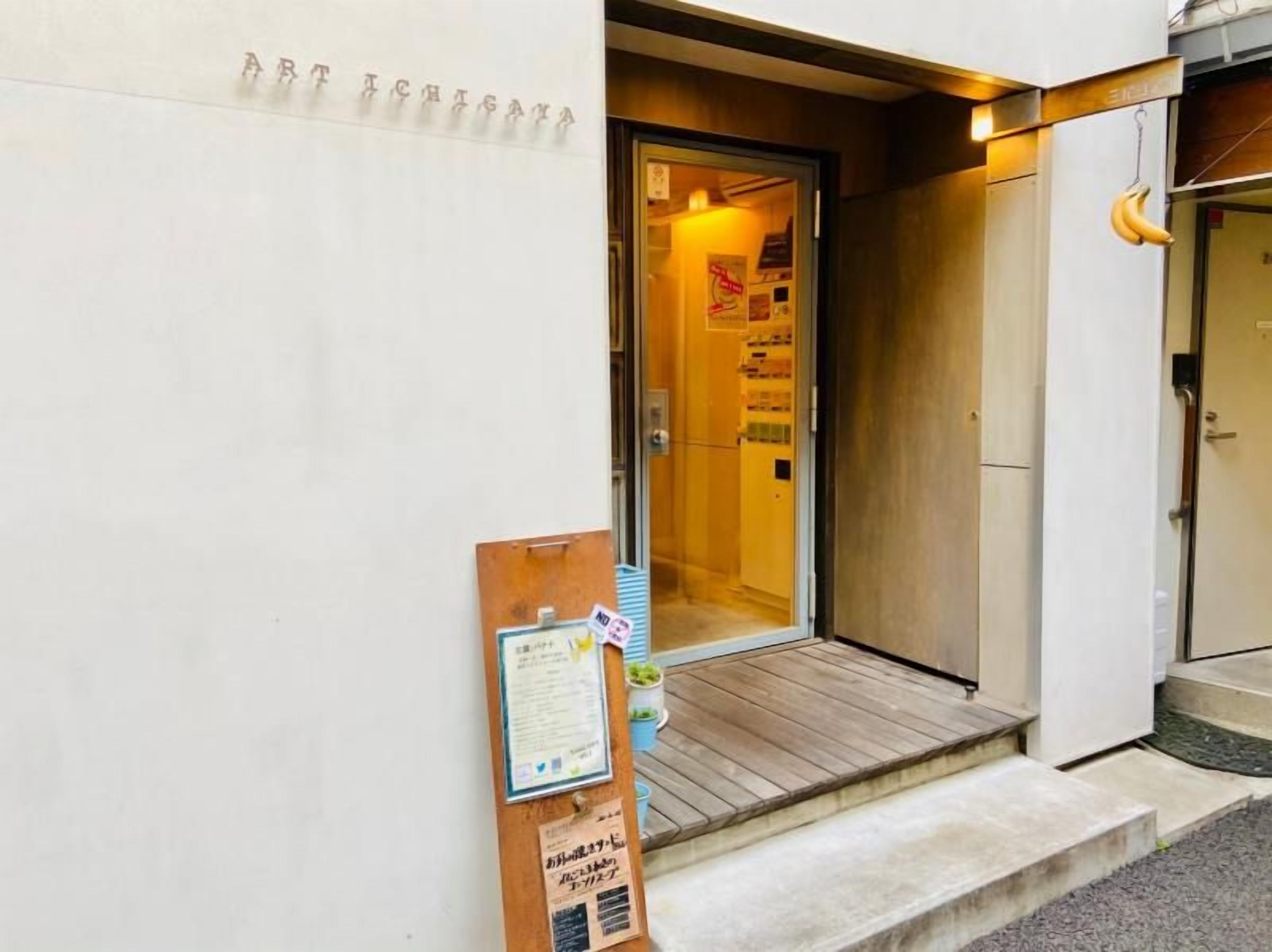 A building entrance with a wooden door, a small porch, and a signboard with text.