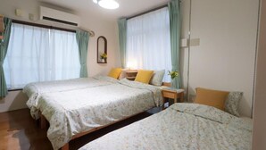 A bedroom with two beds, a bedside table with a lamp, and a window with curtains. - Tokyo Candle house (Shinjuku-ku,)