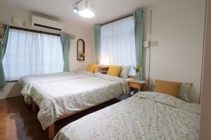 A bedroom with two beds, a bedside table with a lamp, and a window with curtains. - Tokyo Candle house (Shinjuku-ku,)