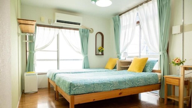 A bedroom with a wooden bed, a bedside table, a mirror, and a window with curtains. - Tokyo Candle house (Shinjuku-ku,)