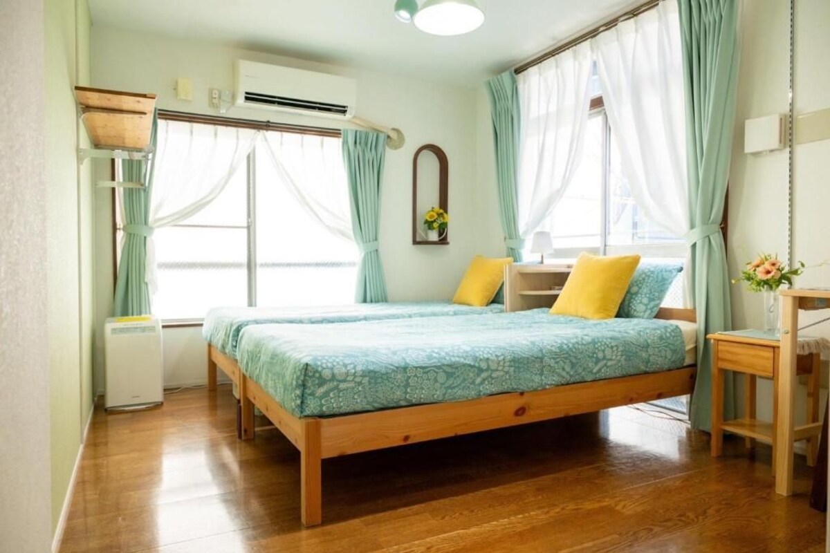 A bedroom with a wooden bed, a bedside table, a mirror, and a window with curtains.