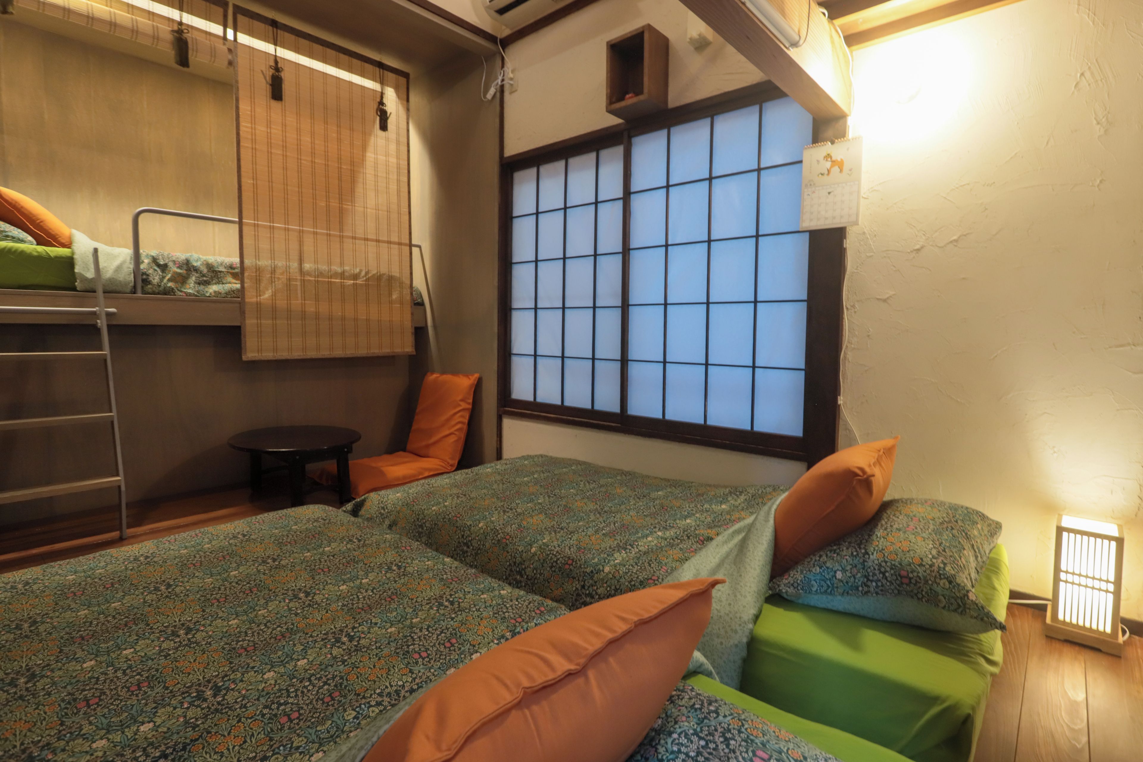 Habitación tipo dormitorio con literas, una mesita y una ventana con diseño de cuadrícula.