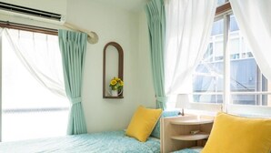 A room with two beds, a small table, and a window with curtains. - Tokyo Candle house (Shinjuku-ku,)