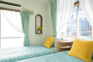 A room with two beds, a small table, and a window with curtains. - Tokyo Candle house (Shinjuku-ku,)