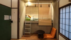 A compact room with a bunk bed, a small table, a chair, and a window with a view. - Tokyo Candle house (Shinjuku-ku,)