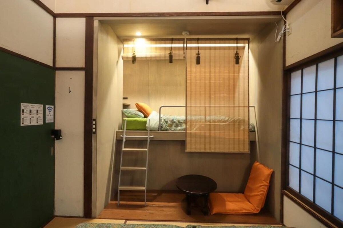 A compact room with a bunk bed, a small table, a chair, and a window with a view.
