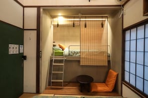A compact room with a bunk bed, a small table, a chair, and a window with a view. - Tokyo Candle house (Shinjuku-ku,)