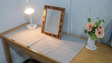 Un comodino con una lampada, uno specchio e un vaso con fiori.