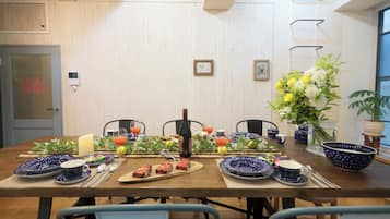 A dining table set with plates, glasses, and a bottle, surrounded by chairs.