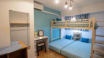 A bunk bed room with a desk and chair, a small table with a lace tablecloth, and an air conditioning unit.