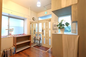 Una habitación con piso de madera, una estantería, una ventana con vista, una puerta con espejo y una planta en maceta.