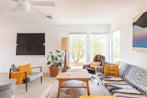 Uma sala de estar moderna com sofá, poltrona e mesa de jantar.