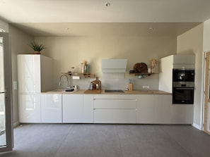 A modern kitchen with white cabinetry, a built-in oven, and a countertop with various kitchen items.
