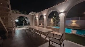 Une terrasse extérieure avec une piscine, une table à manger et des chaises.