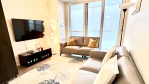 Una sala de estar moderna con un sofá, un televisor de pantalla plana, una mesa de centro y un tapiz estampado.
