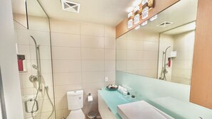 Un baño moderno con cabina de ducha de vidrio, un inodoro blanco y un lavabo con espejo.