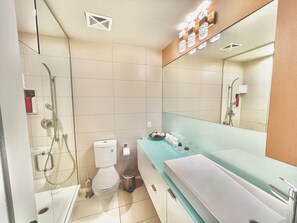 Un baño moderno con cabina de ducha de vidrio, un inodoro blanco y un lavabo con espejo.