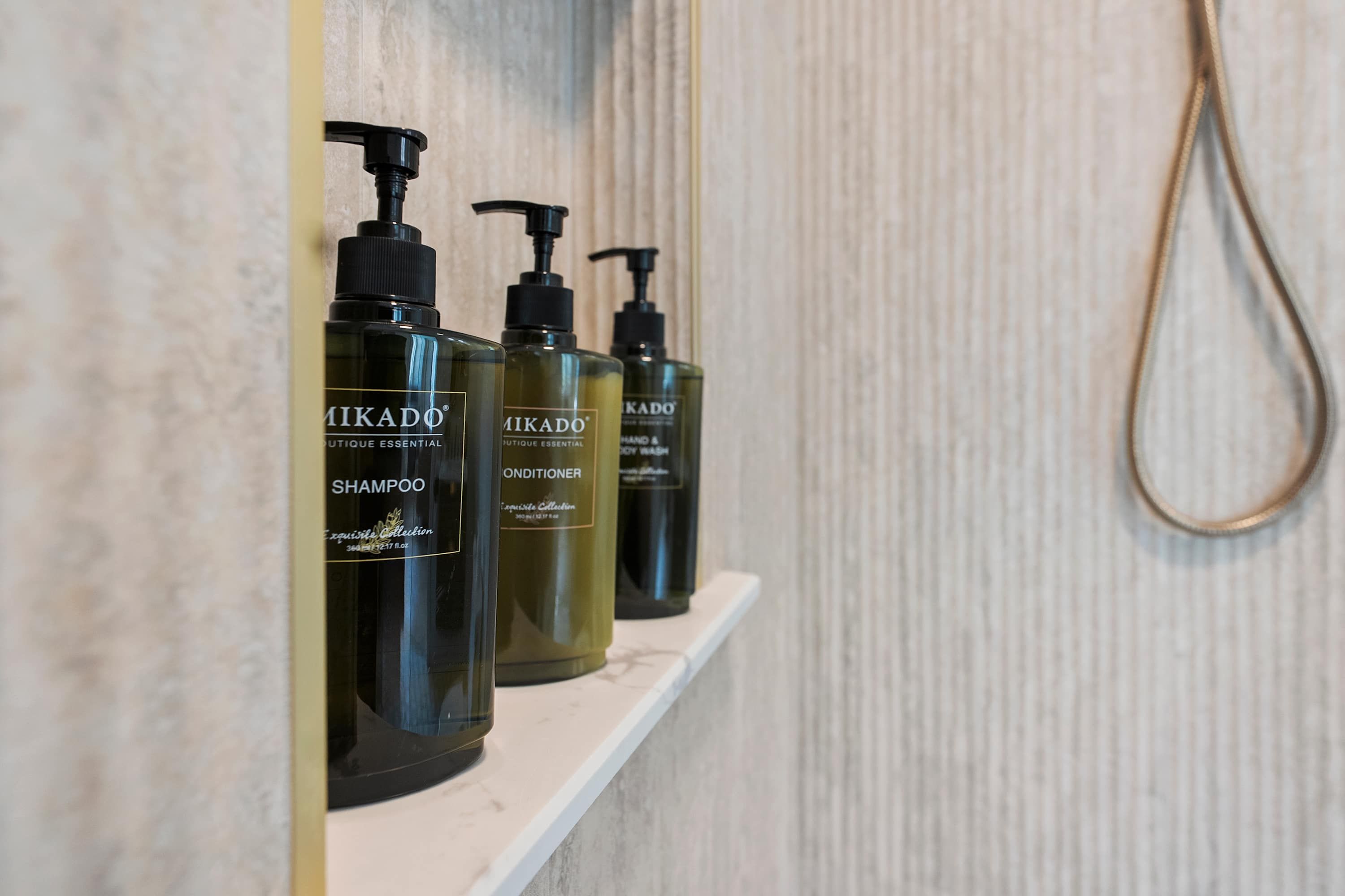 A shelf with three bottles of Mikado shampoo and conditioner.
