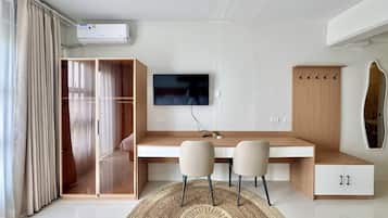Una habitación moderna con escritorio, dos sillas, televisor, armario y espejo.