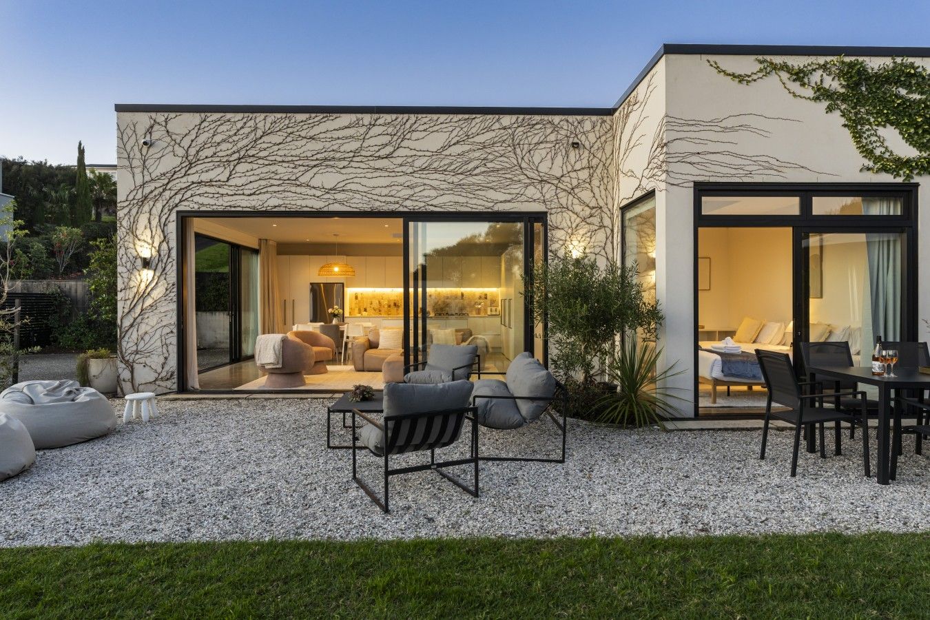 Uma casa moderna com um pátio com área de estar ao ar livre e uma mesa de jantar.