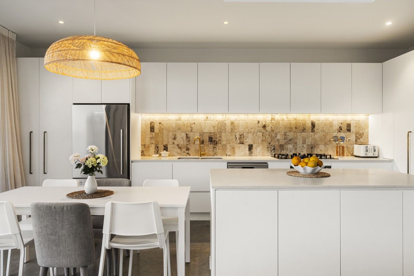 Uma cozinha moderna com armários brancos, uma ilha central e um lustre.
