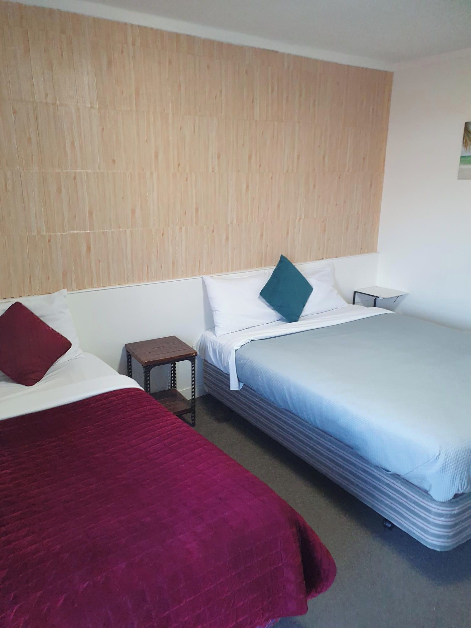 Ein Hotelzimmer mit zwei Betten, einem kleinen Nachttisch und einem Holzkopfstück.
