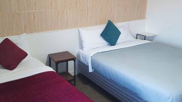 Ein Hotelzimmer mit zwei Betten, einem kleinen Nachttisch und einem Holzkopfstück.