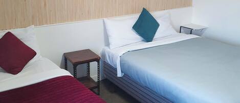 A hotel room with two beds, a small bedside table, and a wooden headboard.