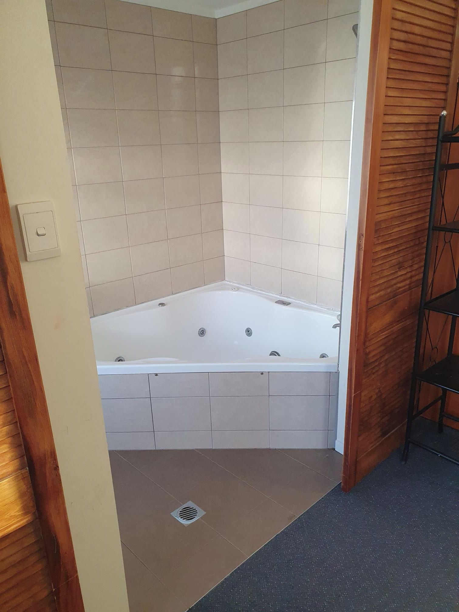 Ein Badezimmer mit einer Badewanne, gefliesten Wänden und einer Holztür.