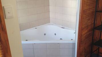 Ein Badezimmer mit einer Badewanne, gefliesten Wänden und einer Holztür.