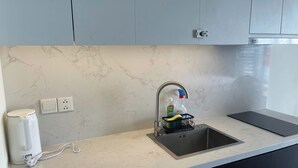 Una cocina con un lavamanos, cafetera y toma de corriente.