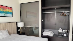 Habitación de hotel con cama, lámpara de noche, armario con perchas y una mesita con radio.