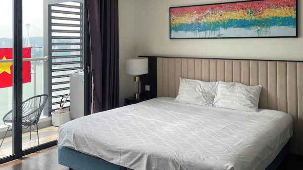 Una habitación de hotel moderna con una cama grande, un cuadro en la pared y vistas al exterior.