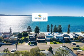 A coastal view of Port Stephens with a prominent sign for Port Stephens Accommodation by Alloggio. - Miramar Coastal Escape (Corlette)