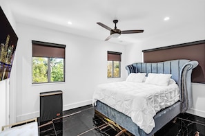 A modern bedroom with a large bed, a ceiling fan, and two windows with blinds. - Outstanding 5-bedroom pool house with AC in marvelous Key Largo (Key Largo)