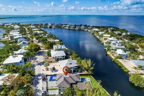 An aerial view of a coastal residential area with houses along a curved waterway, a marked location pin, and a clear sky. - Outstanding 5-bedroom pool house with AC in marvelous Key Largo (Key Largo)