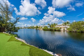 A waterfront property with a swimming pool, a well-maintained lawn, and a clear view of the sky. - Outstanding 5-bedroom pool house with AC in marvelous Key Largo (Key Largo)