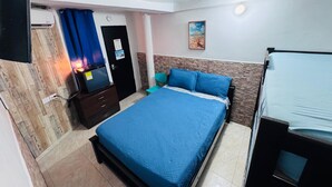 A bedroom with a bed, a desk, a chair, and a door. - Hostal San Andres Vive (San Andrés)