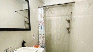 A bathroom with a white sink, a toilet with an orange seat, a shower curtain, and a blue bath mat. - Hostal San Andres Vive (San Andrés)