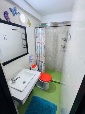 A bathroom with a sink, toilet, shower, and a mirror with butterfly decorations.
